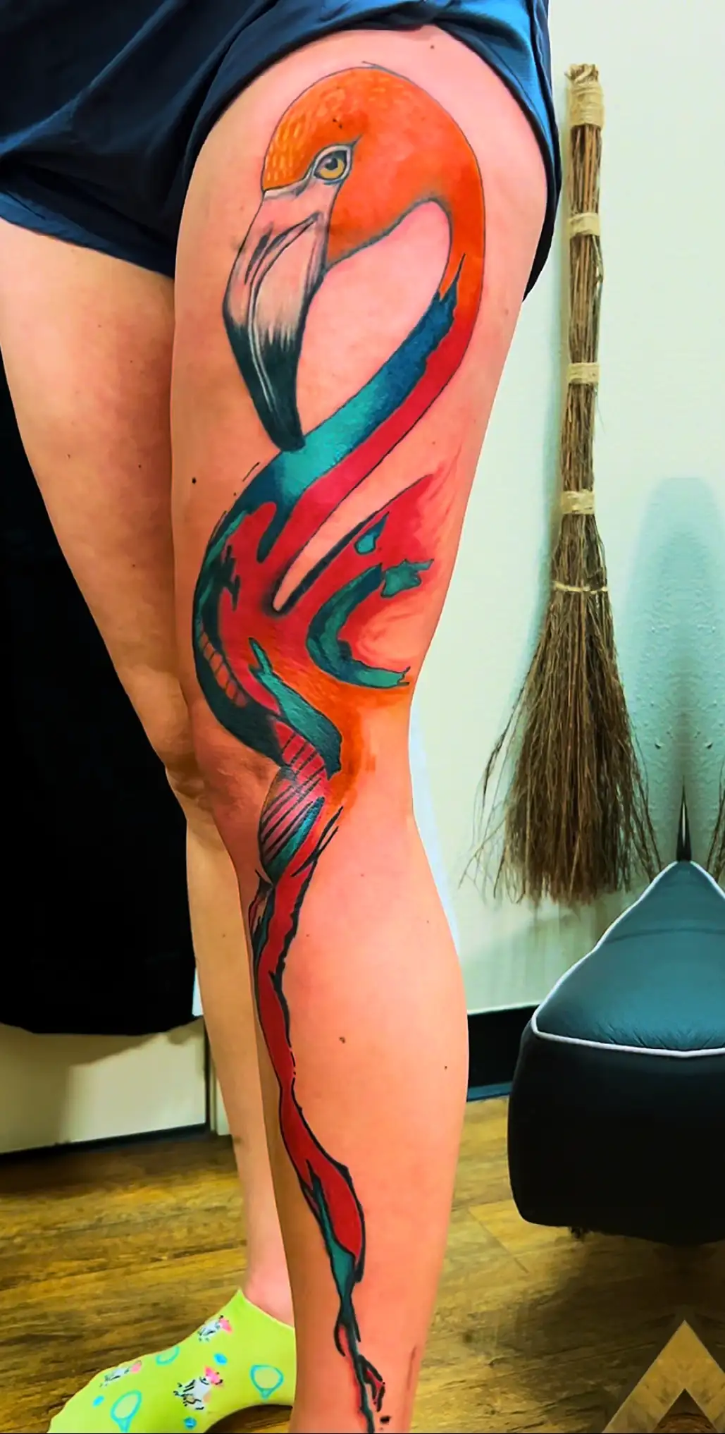 BL-ink Tattoo Colorado Springs full-leg flamingo: bold watercolor orange head with sweeping teal-and-magenta body flowing hip to ankle.